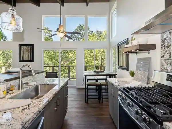 A kitchen with a large window and wooden floors