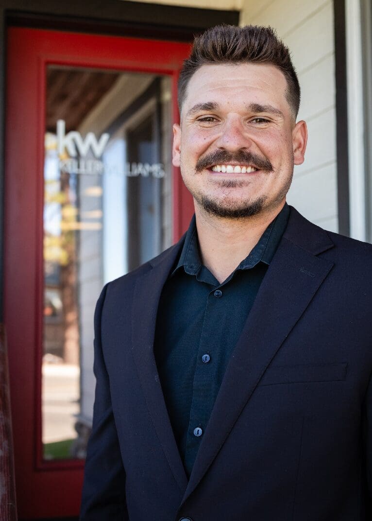 A man with a mustache wearing a suit and smiling.